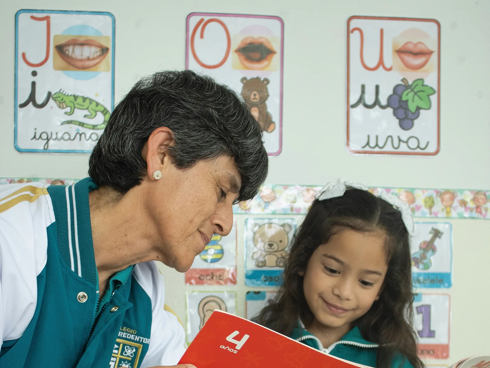 La directora del colegio acompaña a una estudiante durante una actividad de lectura.