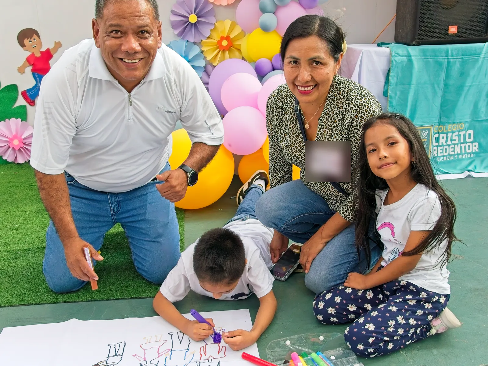 Un padre y una madre dibujan en el patio junto a sus hijos durante el Día de la Familia Redentorina.