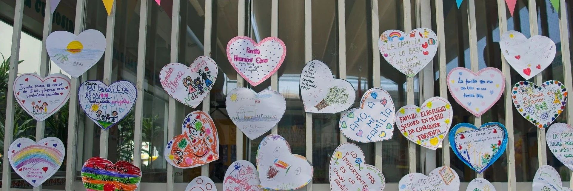 Corazones de papel con mensajes escritos por las familias sobre lo que significa la familia, colgados en el patio durante el Día de la Familia.