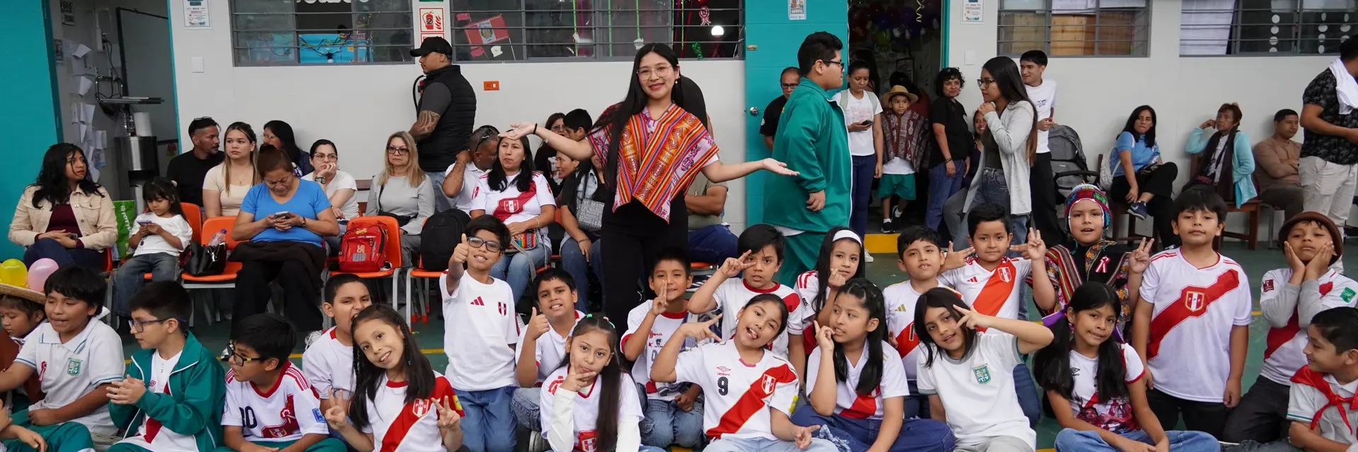 Una maestra celebra con su clase durante las Fiestas Patrias en el patio del colegio.