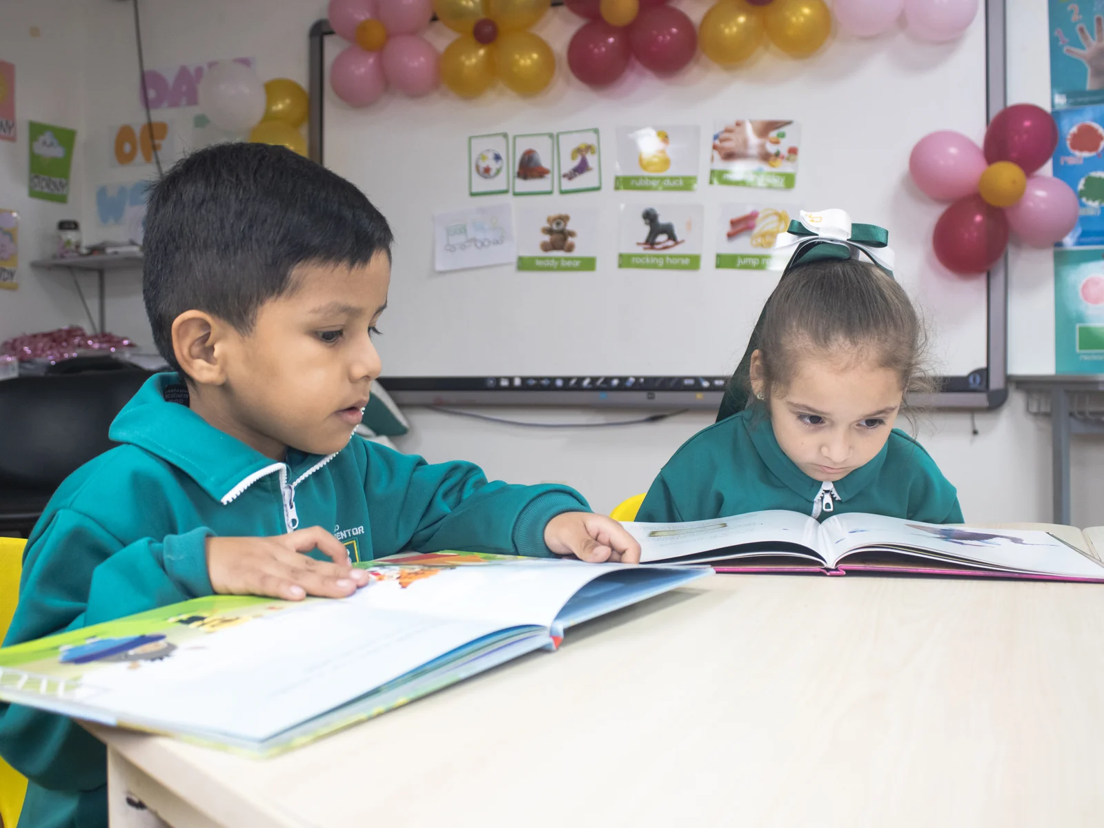 Dos niños leen juntos un libro ilustrado en el aula.
